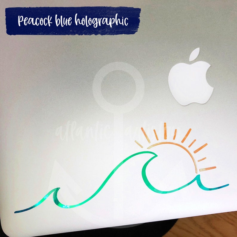 May include: A holographic sticker featuring a wave and sun design. The wave is teal and green, and the sun is orange and yellow. The text "Peacock blue holographic" is in a dark blue rectangle.