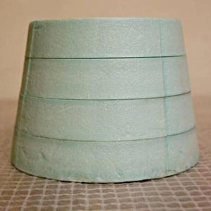 Puede incluir: Un maniquí de pastel de espuma de color azul claro, cilíndrico, con cinco líneas horizontales.