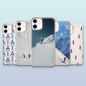 May include: Five different phone cases with winter sports themes. The cases are all clear and show different designs. One case has a colorful pattern of winter hats and skis, another has a snowy mountain scene, another has a skier on a snowy slope, another has a simple white design with a subtle pattern, and another has a white background with a colorful pattern of skiers.