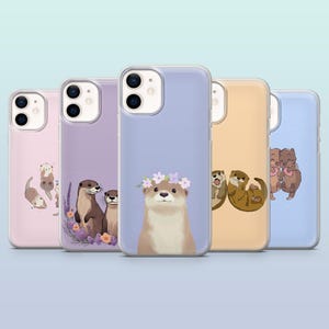 Peut inclure: Cinq étuis de téléphone différents avec des motifs de loutres. Les étuis sont transparents et montrent l'objectif de l'appareil photo du téléphone. Les motifs de loutres sont colorés et comprennent des fleurs, une famille de loutres et une loutre seule.