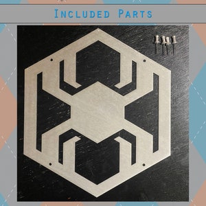 May include: A silver metal wall decor in the shape of a hexagon with a geometric design. The decor is on a black background and comes with five silver push pins.