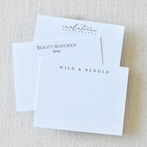 May include: Two white cards with text on them. The top card has the text "ianlatreu photography" and the bottom card has the text "BEAUTY BESPOKEN" with a small leaf design and "WILD & BEHOLD".