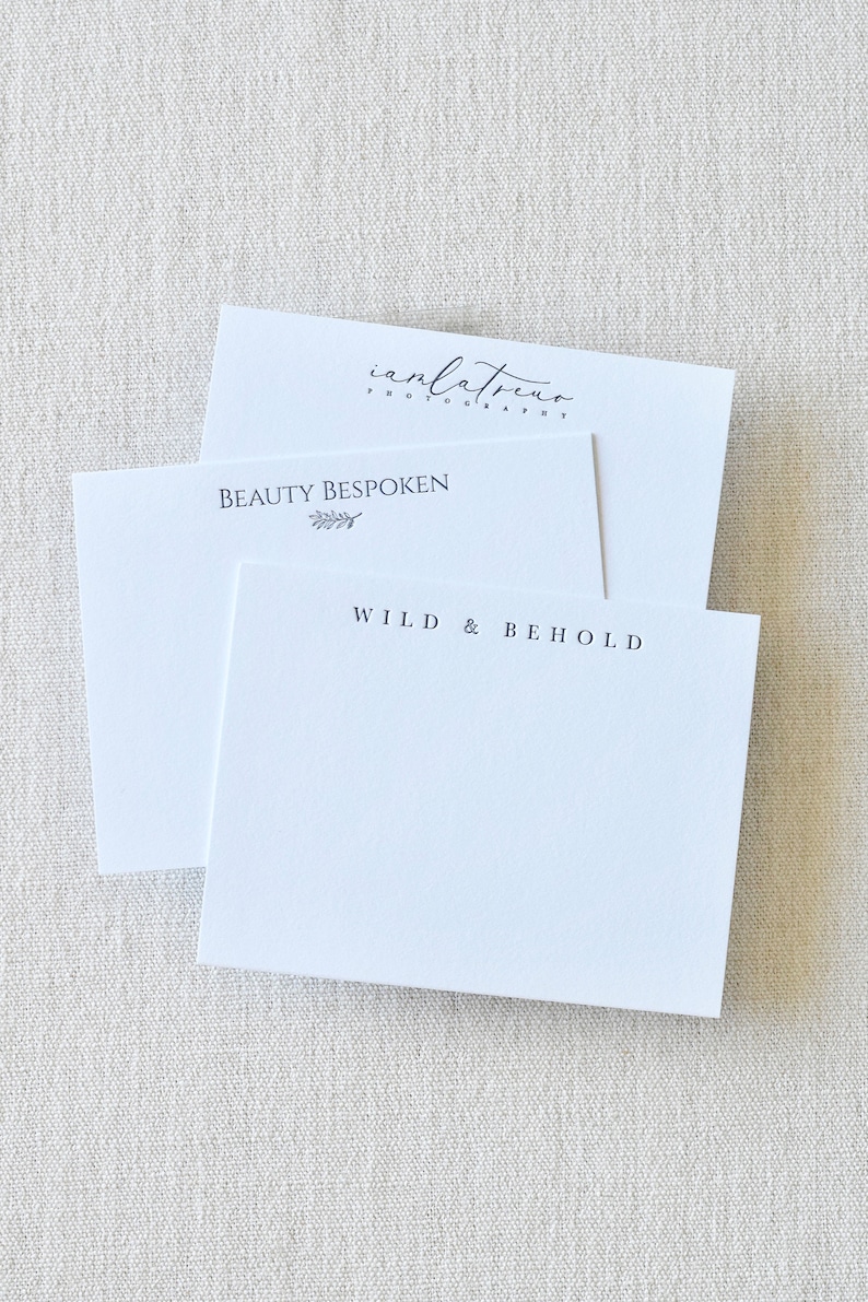 May include: Two white cards with text on them. The top card has the text "ianlatreu photography" and the bottom card has the text "BEAUTY BESPOKEN" with a small leaf design and "WILD & BEHOLD".