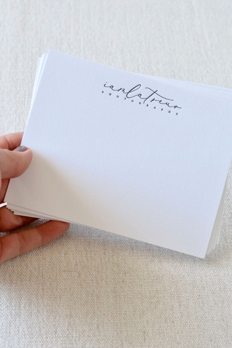 May include: A stack of white note cards with a black and white logo that says "anlatreno photography" printed on the top card.