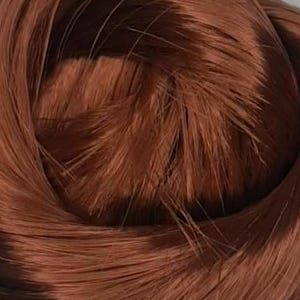 May include: Close-up of a bundle of auburn-colored hair, tightly coiled. The strands are smooth and shiny, with a slight variation in tone, creating depth. The hair appears to be synthetic or processed, with a uniform texture and color throughout.