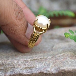 May include: A gold ring set with a large white pearl.