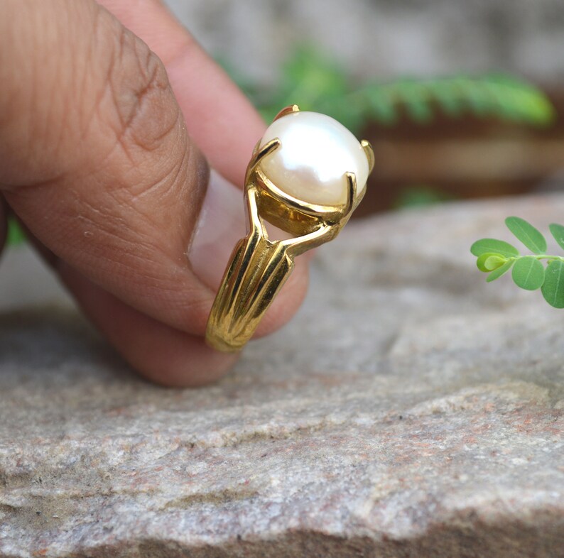 May include: A gold ring set with a large white pearl.
