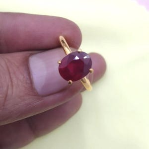 Peut inclure: Une bague en or ornée d'un grand rubis de forme ovale. Le rubis est d'un rouge profond et est maintenu par quatre griffes. L'anneau de la bague est en or poli.