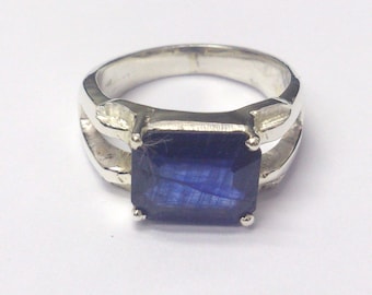 May include: A silver ring with a dark blue rectangular gemstone.