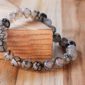 May include: A bracelet made of gray and black agate beads with a black and white marbled pattern.