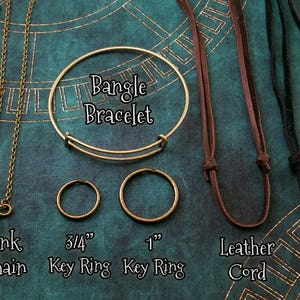 May include: A comparison of different types of necklace chains and cords.  The chains include a ball chain, a link chain, and a bangle bracelet.  The cords include a leather cord and a suede cord.  The chains and cords are shown with key rings in 3/4 inch and 1 inch sizes.