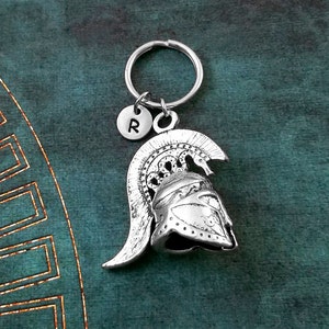 May include: Silver keychain with a charm of a Roman helmet and a letter 'R' charm.