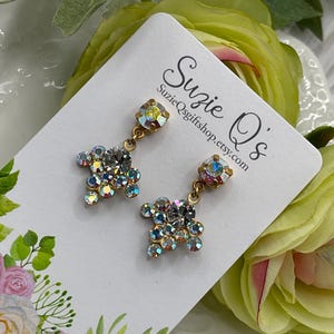 May include: A pair of dangle earrings with a gold tone setting and iridescent crystal accents. The earrings are displayed on a white card with the text "Suzie Q's SuzieQgiftshop.etsy.com".