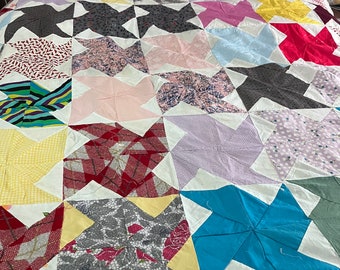 May include: A patchwork quilt with a variety of colorful fabrics and patterns. The quilt is made up of squares with a star design in the center. The quilt is made with a variety of fabrics, including floral prints, plaid, and solid colors.