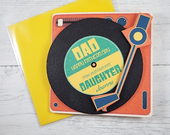 May include: A card with a pop-up record player design. The record is black with a green and yellow circle that says "Dad Happy Father's Day From Your Favourite Daughter Joanna".