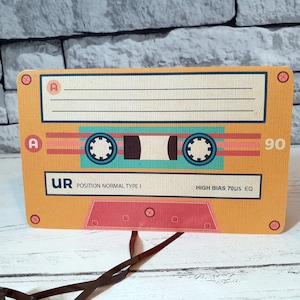 May include: A yellow cassette tape with a black and blue tape reel. The tape is labeled "UR POSITION NORMAL TYPE I HIGH BIAS 70uS EQ 90".