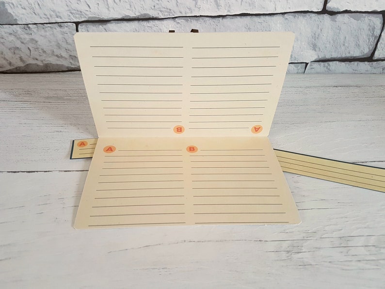 May include: A cream-colored notebook with lined pages and four orange letter stickers labeled "A" and "B".