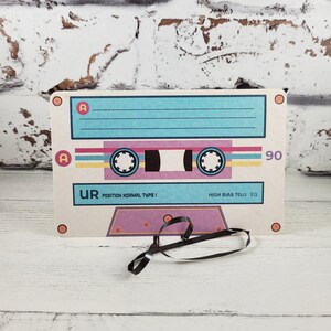 May include: A vintage-style cassette tape mockup with a light blue background, pink and yellow stripes, and the text "UR POSITION NORMAL TYPE I HIGH BIAS 70uS EQ 90".