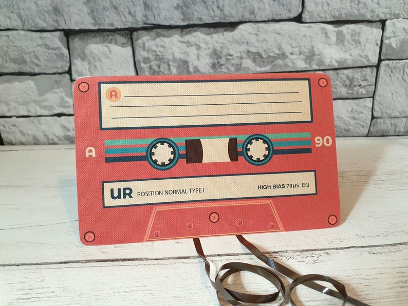 May include: A red cassette tape with the text "UR POSITION NORMAL TYPE I HIGH BIAS 70&micro;S EQ" and the number "90" printed on it.