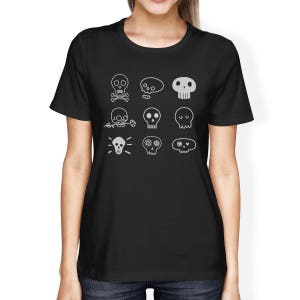 May include: Black t-shirt with a white design of various skull illustrations. The skulls have different features, including flowers, eyes, and a lightbulb.