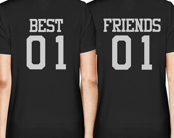 Puede incluir: Dos camisetas negras con texto blanco en la espalda. Una camiseta dice "BEST 01" y la otra dice "FRIENDS 01".