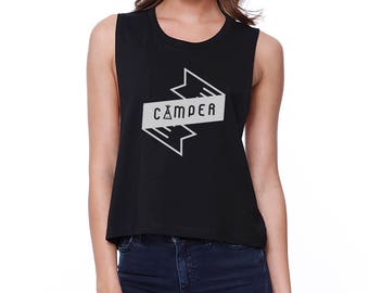 May include: Black sleeveless crop top with a white graphic of a stylized arrow with the word "CAMPER" inside.