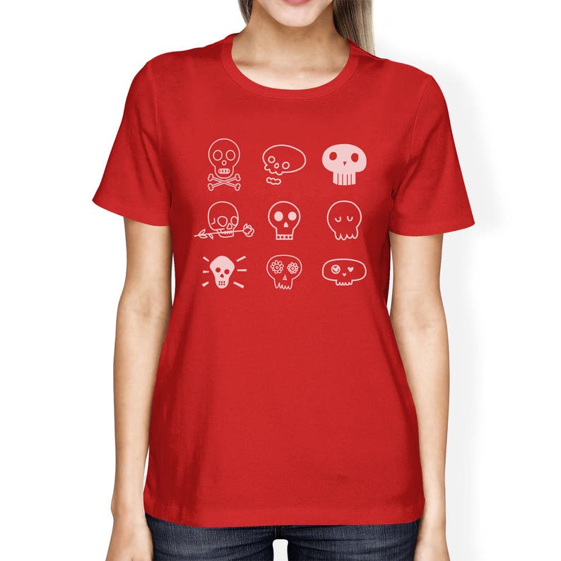 May include: Red t-shirt with a white design of various skull illustrations. The skulls have different expressions and details, including flowers, crossbones, and eyes.