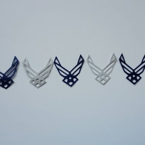 May include: Five paper cut-outs of the United States Air Force emblem. The cut-outs are in a row, with the leftmost cut-out being a solid blue colour, the next two cut-outs being a gradient of blue to white, the next cut-out being a solid white colour, and the rightmost cut-out being a solid blue colour.