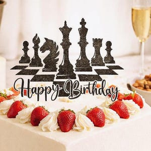 Pode incluir: Um bolo de aniversário quadrado com cobertura branca, coberto com morangos e chantilly. Um topo de bolo preto com peças de xadrez com "Happy Birthday" é colocado em cima. Uma taça de champanhe está no fundo.
