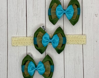 Op de afbeelding: Drie groene en blauwe gelaagde stoffen strikken met gouden glitteraccenten. De strikken zijn bevestigd aan een wit elastisch hoofdband.