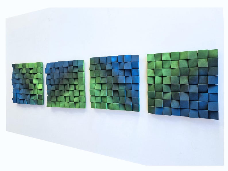 a series of three abstract artworks displayed on a white wall. Each artwork consists of a collection of small square tiles in various shades of green and blue, arranged in a grid-like pattern. The artworks are arranged in a row, creating a visually appealing and harmonious display.