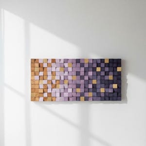 a rectangular wooden block art piece with a gradient of purple and orange colors, mounted on a white wall.