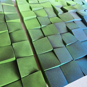 a close-up view of a collection of green and blue geometric shapes, possibly composed of small cubes or blocks, arranged in a visually striking pattern.