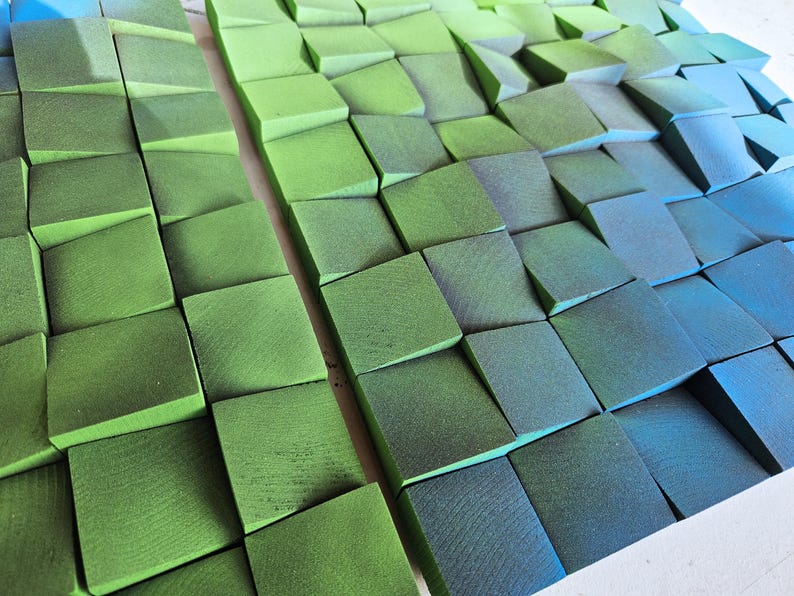 a close-up view of a collection of green and blue geometric shapes, possibly composed of small cubes or blocks, arranged in a visually striking pattern.