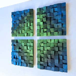 four square-shaped sculptures made of small, colorful blocks arranged in a grid-like pattern on a white background.