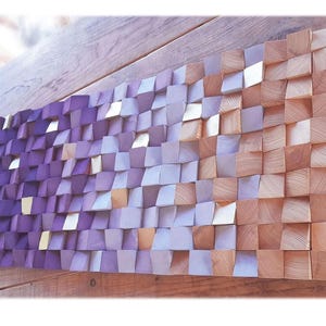 a wooden surface with a textured, mosaic-like pattern composed of small, square-shaped wooden blocks in various shades of purple and orange.