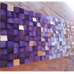 a wooden surface with a textured, mosaic-like pattern composed of small square tiles in various shades of purple and orange.