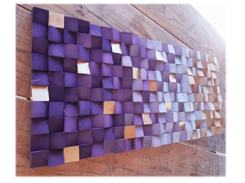 a wooden surface with a textured, mosaic-like pattern composed of small square tiles in various shades of purple and orange.