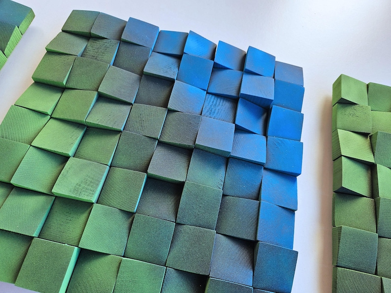 a close-up view of a collection of square-shaped objects, likely composed of various materials, arranged in a grid-like pattern. The objects appear to be made of wood, with some having a green and blue color scheme. The objects are arranged in a way that they create a visually interesting and textured surface.