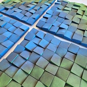 a close-up view of a collection of small, square-shaped objects in various shades of blue and green, arranged in a grid-like pattern.