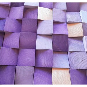 The image is a close-up of a collection of wooden blocks in various shades of purple and beige, arranged in a grid-like pattern.