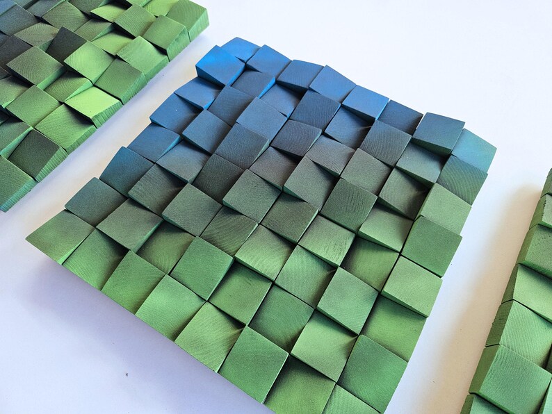 a square-shaped arrangement of green and blue wooden blocks, creating a visually striking and geometric pattern.