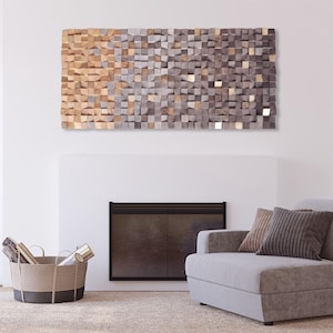 a living room with a gray sofa, a woven basket, and a fireplace. Above the fireplace, there is a large abstract art piece composed of small square tiles in various shades of brown and gray.