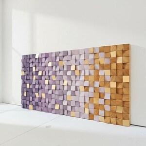 a large, colorful wall made up of numerous small square tiles in shades of purple and gold. The tiles are arranged in a visually striking pattern, creating a vibrant and eye-catching display.