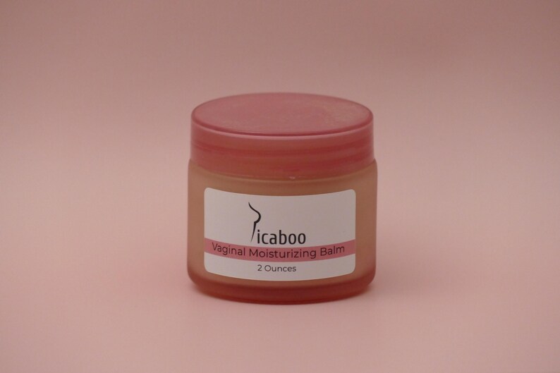 Pu&ograve; includere: Un piccolo barattolo rotondo con coperchio rosa ed etichetta bianca. L'etichetta recita "Picaboo Vaginal Moisturizing Balm" e "2 once". Il barattolo &egrave; riempito con un balsamo di colore chiaro su sfondo rosa.