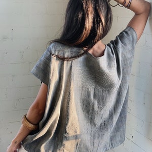 May include: A grey cotton blouse with a geometric pattern. The blouse has short sleeves and a loose fit.