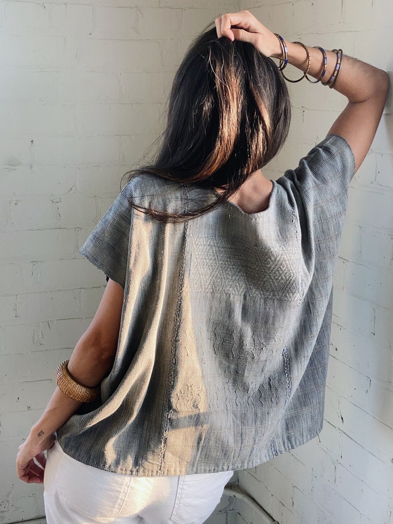 May include: A grey cotton blouse with a geometric pattern. The blouse has short sleeves and a loose fit.