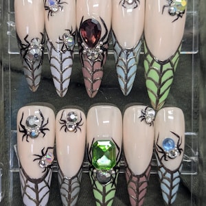 May include: Set of ten false nails with spider web designs and spider accents. Some nails have rhinestones and gems in various colors.