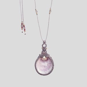 Peut inclure: Un collier en macramé gris avec un pendentif en perle et en coquille.