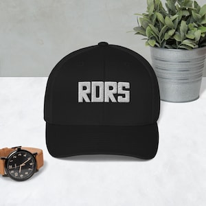 May include: Black baseball cap with a white embroidered logo that says "RDRS".